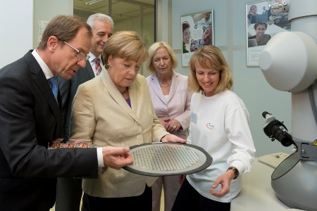 CEO Reinhard Ploss explains German Chancellor Angela Merkel the structure of a power chip on a 300mm thinwafer F.l.t.r: Dr. Reinhard Ploss (CEO Infineon Technologies AG), Stanislaw Tillich (Prime Minister of Saxony), Dr. Angela Merkel (Chancellor of Germany), Prof. Dr. Johanna Wanka (Federal Minister of Education and Research), Infineon employee.