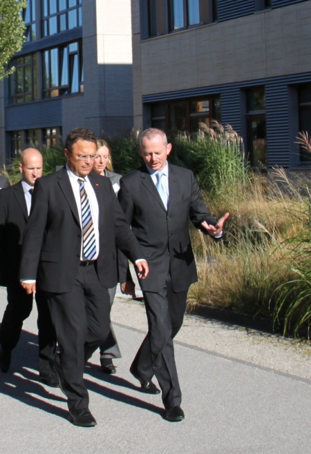 Der Bundesminister des Innern, Dr. Hans-Peter Friedrich (links), und Peter Bauer, Vorstandsvorsitzender der Infineon Technologies AG, am Unternehmenssitz von Infineon in Neubiberg bei München auf dem Weg zu Infineons Sicherheitslabors.
