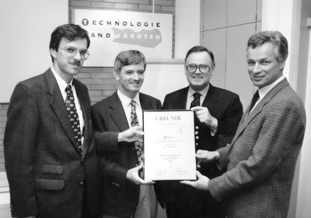 Wolfgang Pribyl (links), EZM-Leiter von 1993 bis 1998, und Horst Seitz (Zweiter von rechts), kaufmännischer Leiter der Siemens Bauelemente OHG, nehmen den Forschungspreis des Landes Kärnten entgegen
