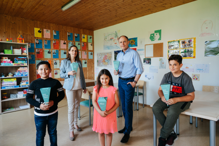 Schoolbags for the school start: Oliver Heinrich, CFO of nfineon Austria, and Mag. Marion Fercher, Commercial Director of Caritas Carinthia, with children of the Caritas Lerncafé in Villach. 